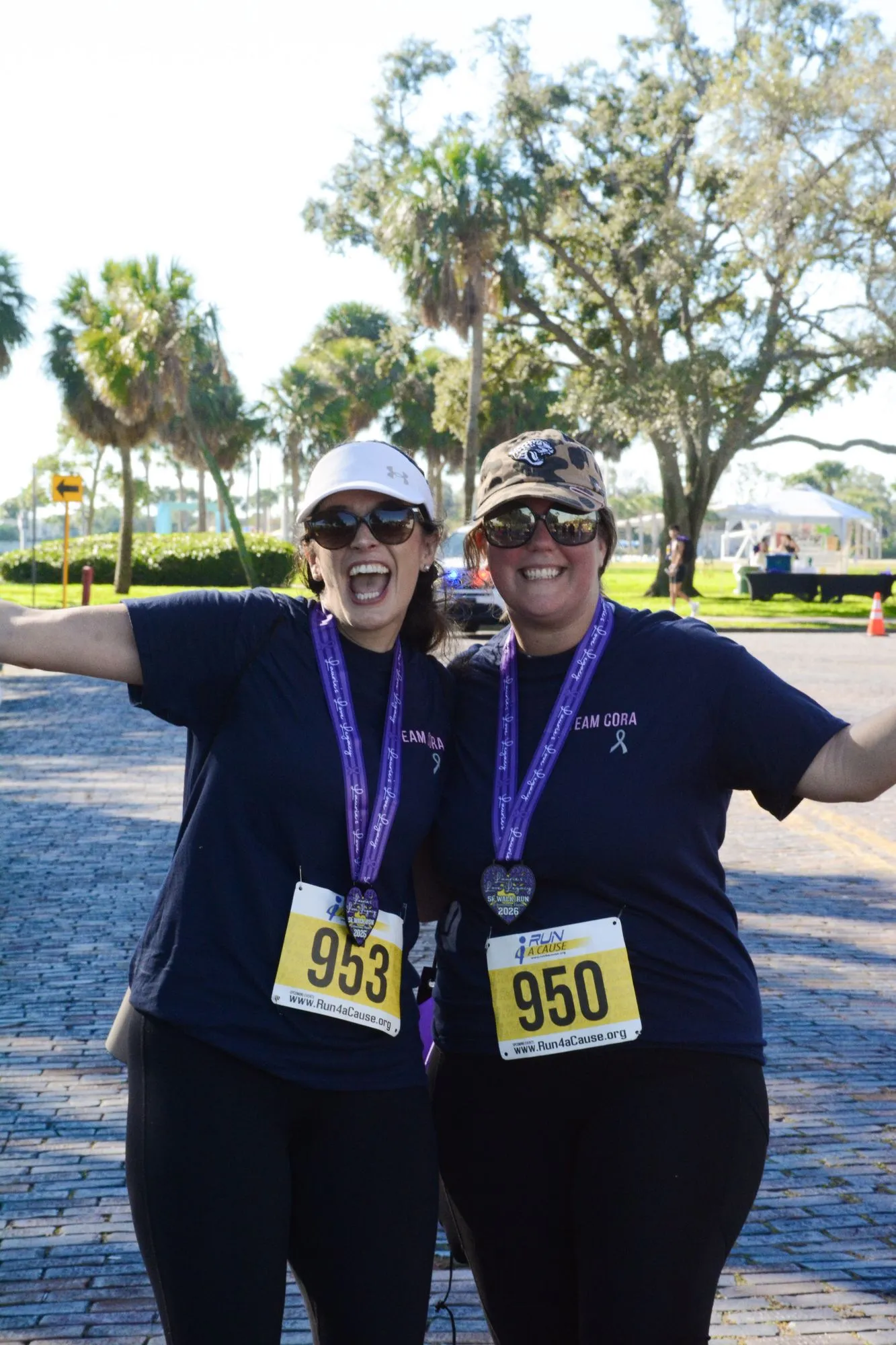 Two women smile with their finisher medals after the 2026 Legacy Run