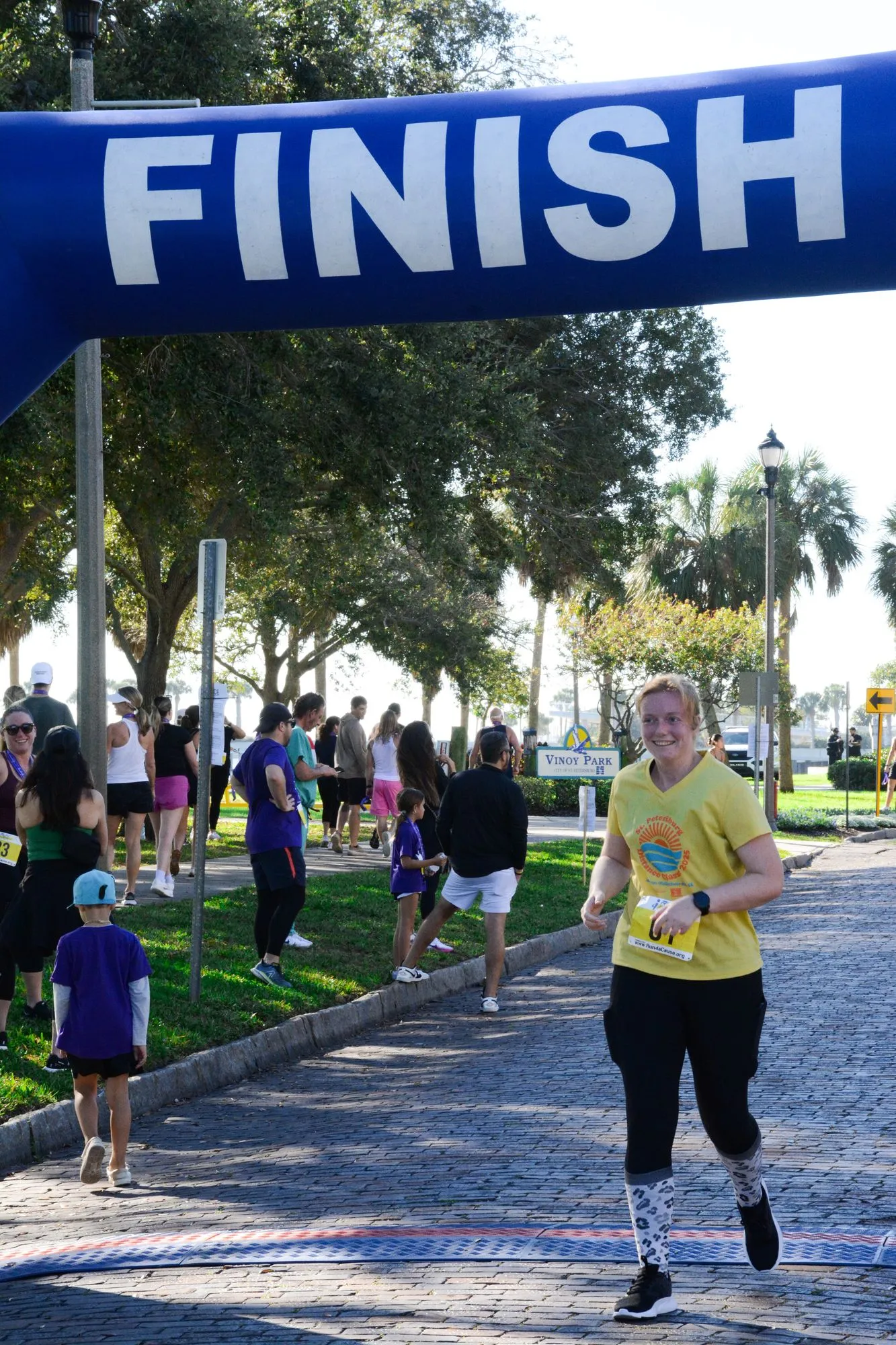 A runner crosses under the finish arch at the 2026 Laurie’s Love Legacy Run as the crowd looks on